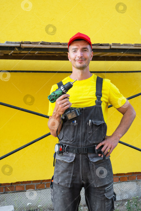 Скачать Портрет строителя с дрелью и уровнем в руках, строительная площадка, проект дома своими руками, инструменты для ремонта, частный бизнес разнорабочих, услуги на дому. фотосток Ozero
