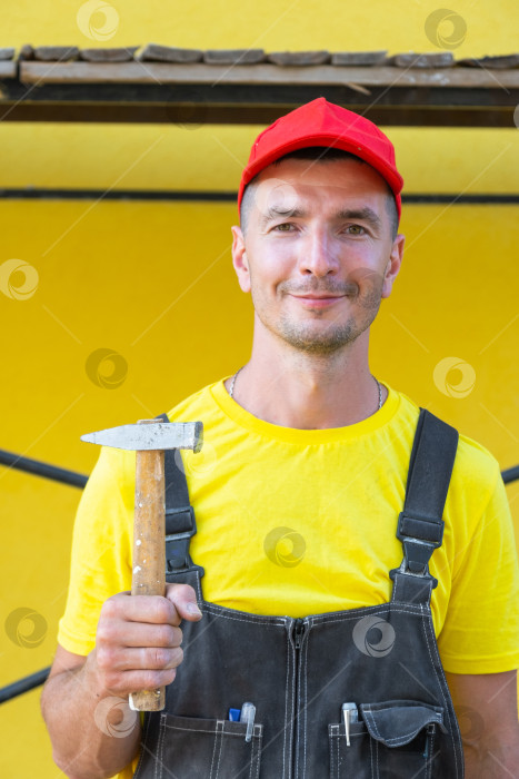 Скачать Портрет строителя в красной шапочке с молотком в руках, частный мастер на все руки, ремонт дома, столярные работы, строительство своими руками на месте, эксперт по строительству дома. фотосток Ozero