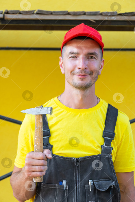 Скачать Портрет строителя в желтой рубашке с молотком, частный ремонтный бизнес, забивание гвоздей, обрамление, плотницкие работы, выезд на дом, навыки "сделай сам". фотосток Ozero