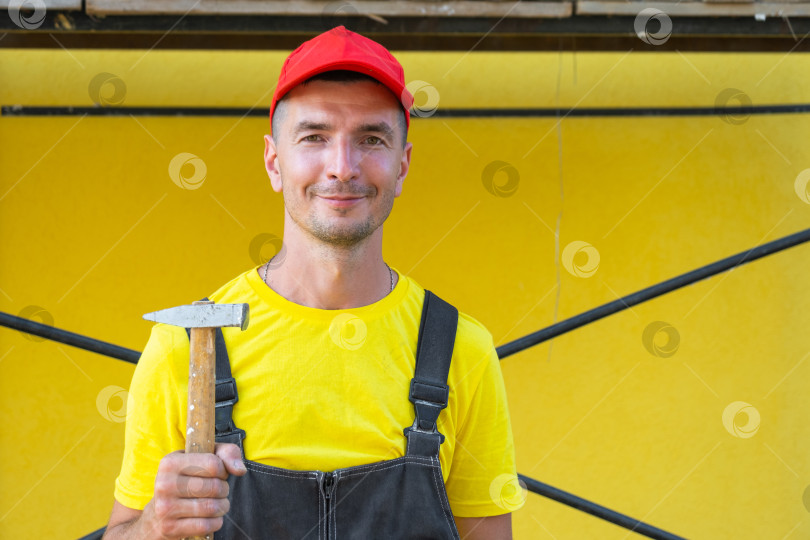 Скачать Портрет специалиста по благоустройству дома с молотком, жилищное строительство, забивание гвоздей, обрамление, техника "сделай сам", частный ремонтный бизнес на месте, услуги разнорабочего. фотосток Ozero