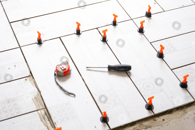 Скачать Процесс укладки напольной плитки, система выравнивания, точное размещение, ремонтные работы, инструменты для укладки керамической плитки, проект благоустройства дома. фотосток Ozero