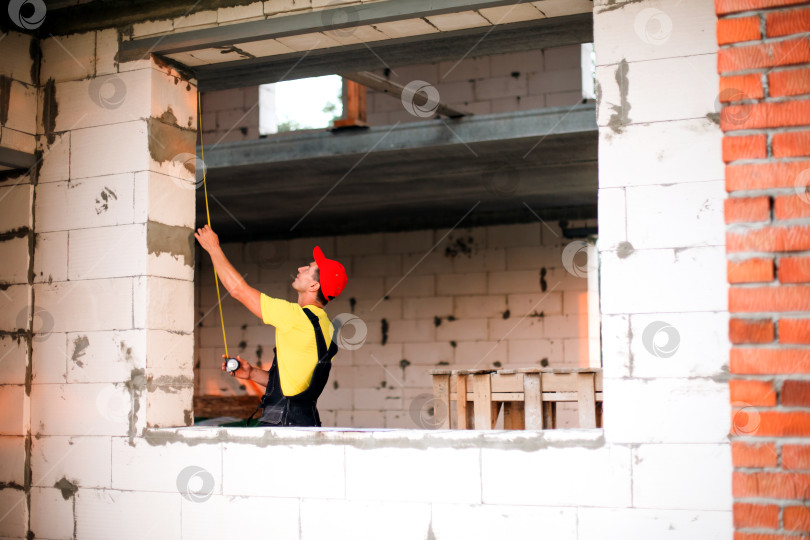 Скачать Замер оконного проема геодезистом, подготовка к установке окна, работы на строительной площадке, проверка размера рамы, специалист по ремонту и перепланировке дома. фотосток Ozero