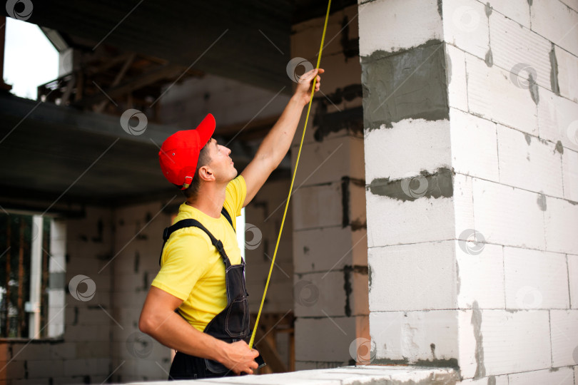 Скачать Геодезист измеряет высоту стен, оконные и дверные проемы, новую конструкцию, разметку перед установкой, конструкцию и расположение перегородок для будущих работ. фотосток Ozero