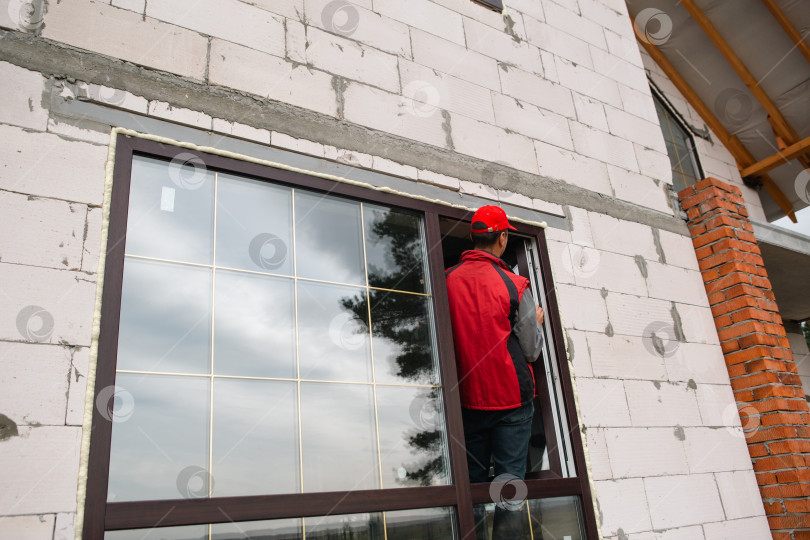 Скачать Монтажник окон занимается установкой ПВХ-рам в новом доме, точным выравниванием и регулировкой, профессиональным обслуживанием современного бизнеса по установке окон на дому. фотосток Ozero