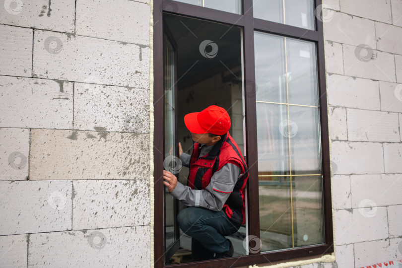 Скачать Опытный оконный мастер проводит тонкую настройку установки новых пластиковых окон, детальное регулирование комфорта и теплоизоляции, современный строительный бизнес. фотосток Ozero
