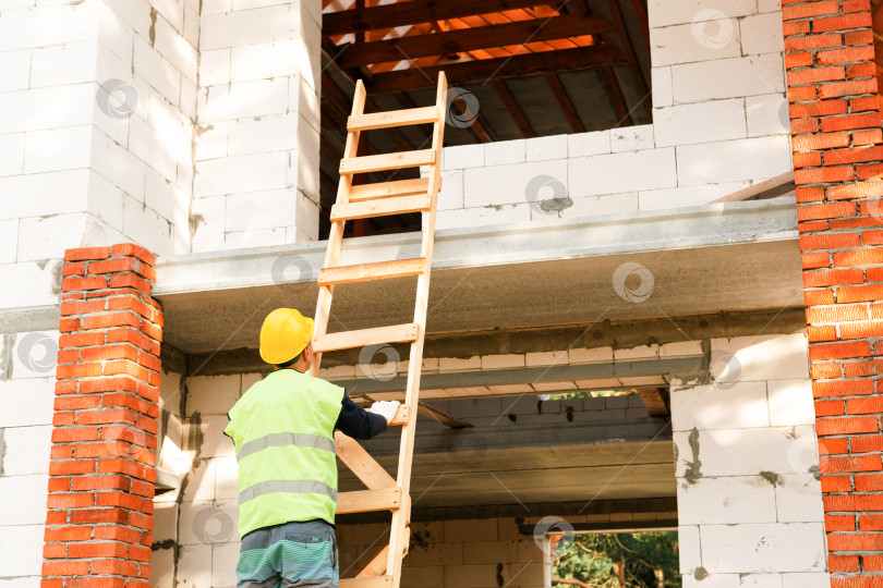 Скачать Строитель готовится подняться на строительные леса, строительство дома, организация, защитный жилет, настройка проекта, начало сборки новой конструкции, профессиональная работа. фотосток Ozero