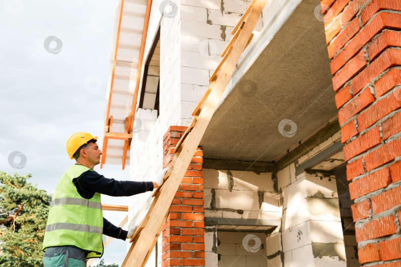 Скачать Строитель у стены, проверяет выравнивание, начинает процесс строительства, измеряет высоту, каменщик, задание бригады, подготовка к монтажу, техническая проверка. фотосток Ozero