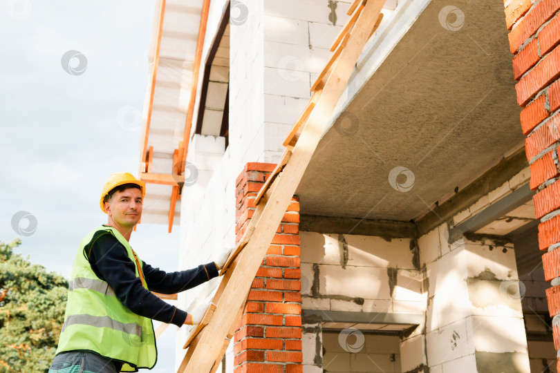 Скачать Строитель удерживает балку для поддержки конструкции, позиционирует стеновой элемент, оценивает высоту, координирует работу команды, управление строительным участком, подготовку к ремонту, установку кирпичной кладки. фотосток Ozero