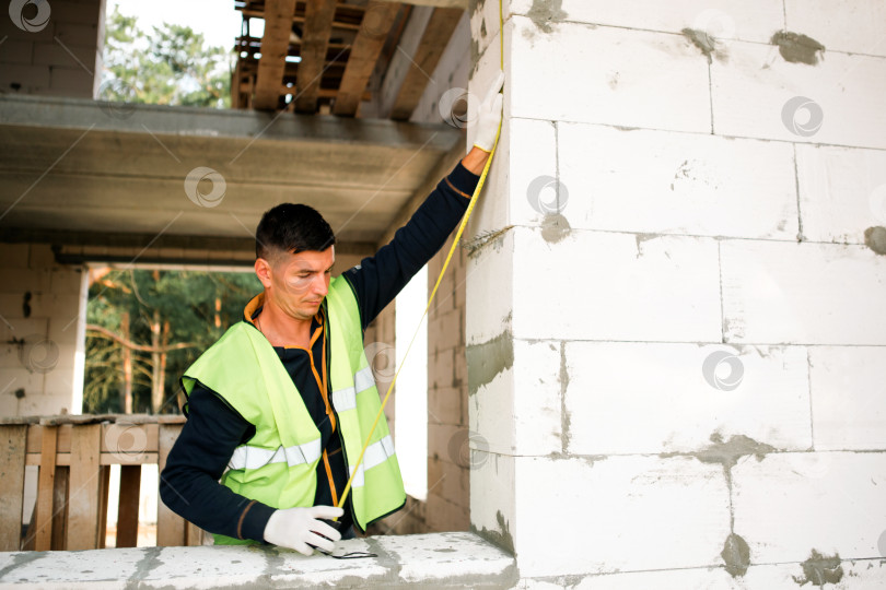 Скачать Профессиональный строитель устанавливает изоляцию, обрабатывает стены, работает в команде, обеспечивает тепловую защиту здания, этапы ремонта дома, планирование, крепления, работы на стройплощадке. фотосток Ozero