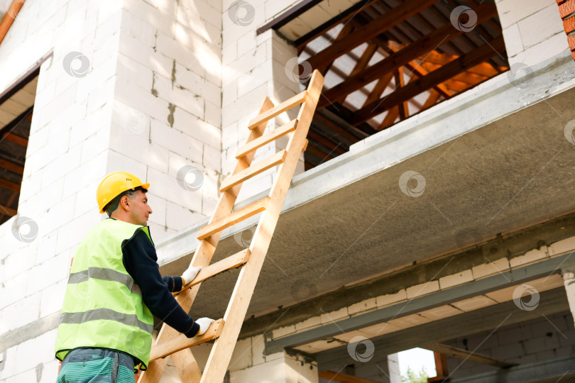 Скачать Профессиональный строитель организует лестницу и балки, готовится к следующему этапу, установке стеновых конструкций, логистике совместной работы, началу строительства, проверке безопасности. фотосток Ozero