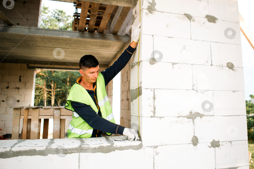 Скачать Застройщик проверяет вертикальный уровень, выравнивание стен, измерение площадки, планирование строительства, профессиональный осмотр, ремонт дома, командную работу, контроль хода работ. фотосток Ozero