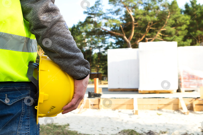 Скачать Профессиональный строитель держит в руках защитный шлем, осматривает строительную площадку, проверяет ход реализации проекта, управление, планирование, надзор за строительными работами, контроль оборудования. фотосток Ozero