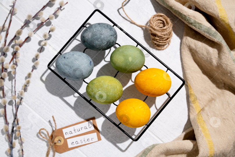 Скачать Пасхальные яйца, окрашенные естественным образом гибискусом и куркумой, сохнут на решетке для охлаждения, создавая красивую палитру желтых и зеленых оттенков, готовые к празднованию Пасхи фотосток Ozero