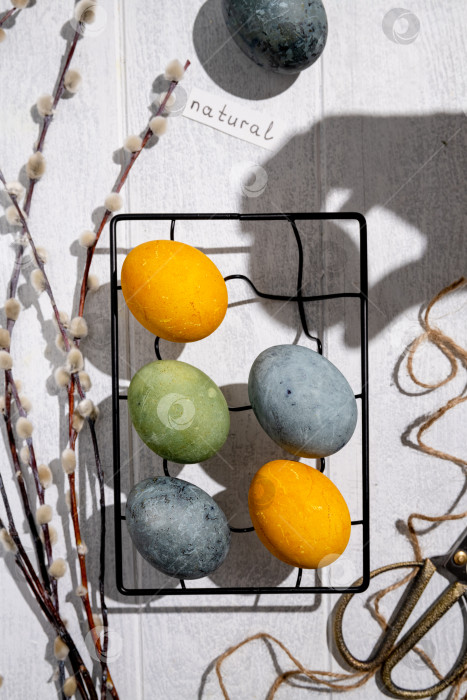 Скачать Пасхальные яйца, окрашенные естественным образом гибискусом и куркумой, сохнут на решетке для охлаждения, создавая красивую палитру желтых и зеленых оттенков, готовые к празднованию Пасхи фотосток Ozero