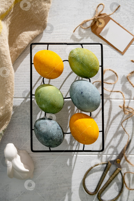 Скачать Пасхальные яйца, окрашенные естественным образом гибискусом и куркумой, сушатся на охлаждающей решетке, создавая красивую палитру желтых и зеленых оттенков, готовые к празднованию Пасхи с помощью copy space. фотосток Ozero