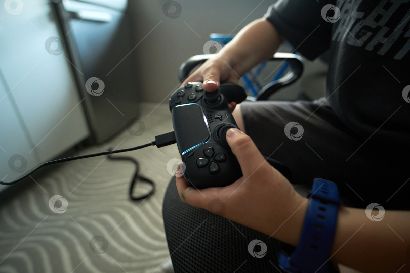 Скачать Тюмень, Россия - 8 июля 2025 года: Ребенок на Sony PlayStation 5 днем играет дома с консольным контроллером. фотосток Ozero