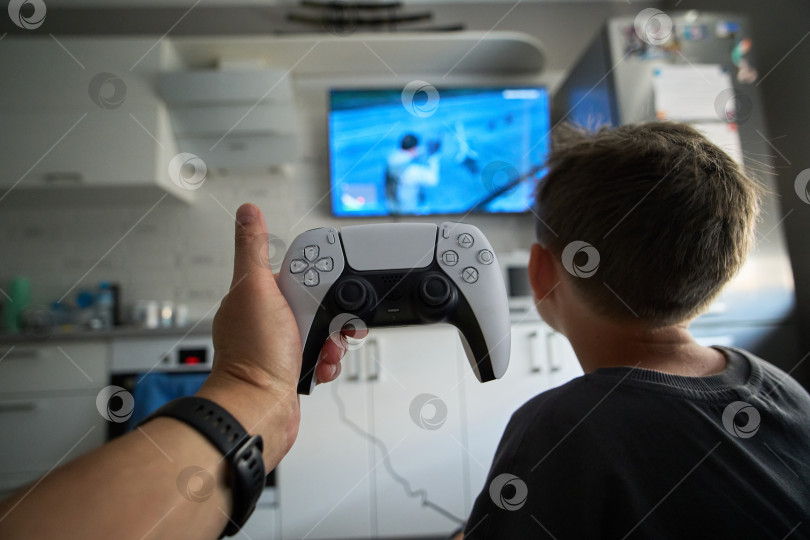 Скачать Тюмень, Россия - 8 июля 2025 года: Ребенок на Sony PlayStation 5 днем играет дома с консольным контроллером. фотосток Ozero