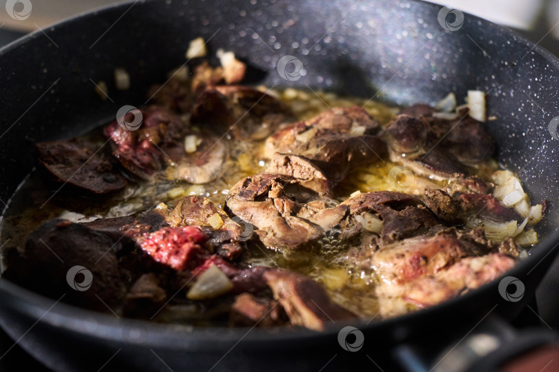 Скачать Приготовление кусочков печени на сковороде с поднимающимся паром на фоне кухонных приборов фотосток Ozero