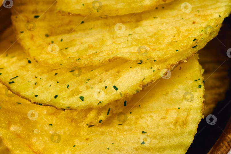 Скачать Золотистые картофельные чипсы выложены аккуратными слоями, демонстрирующими их ребристую текстуру фотосток Ozero