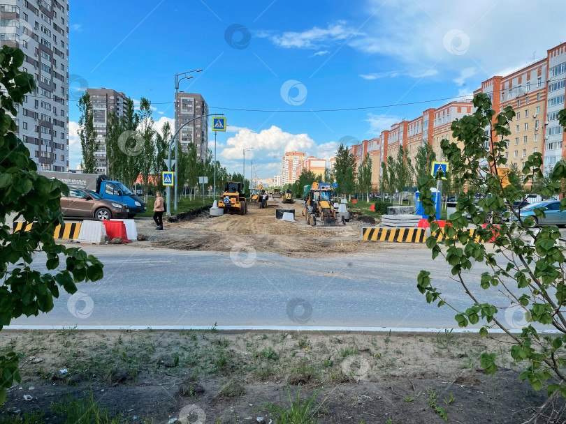 Скачать Тюмень, Россия - 10 июня 2025 года: Тяжелая техника работает на строительстве дороги вдоль оживленной городской улицы фотосток Ozero
