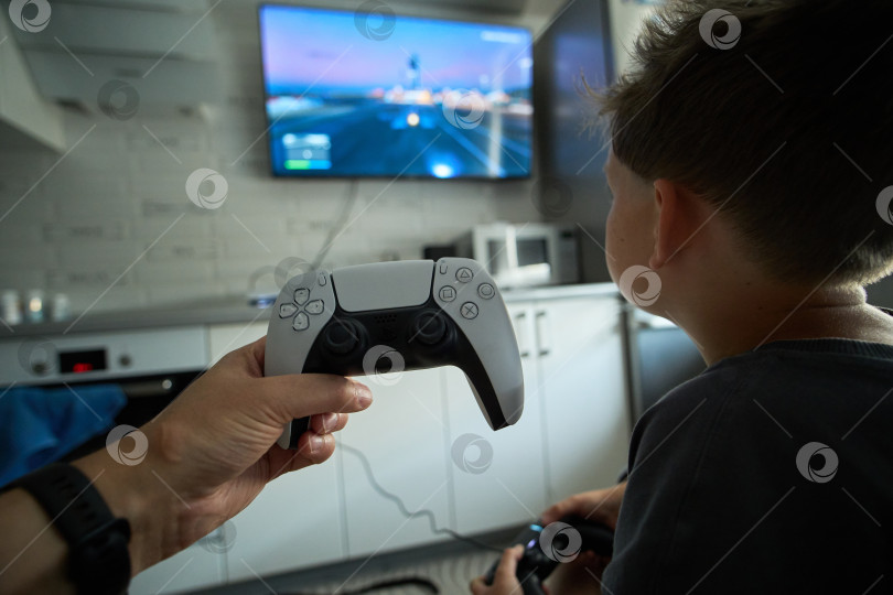 Скачать Тюмень, Россия - 8 июля 2025 года: Sony PlayStation 5 Человек сосредоточен на игровом контроллере, погружен в свой игровой опыт фотосток Ozero