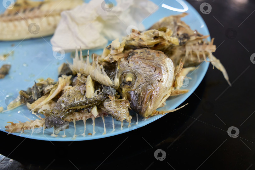 Скачать Вкуснейшая рыба дорадо, поданная на тарелке, демонстрирует хрустящую золотистую кожицу и нежные косточки после сытного ужина фотосток Ozero