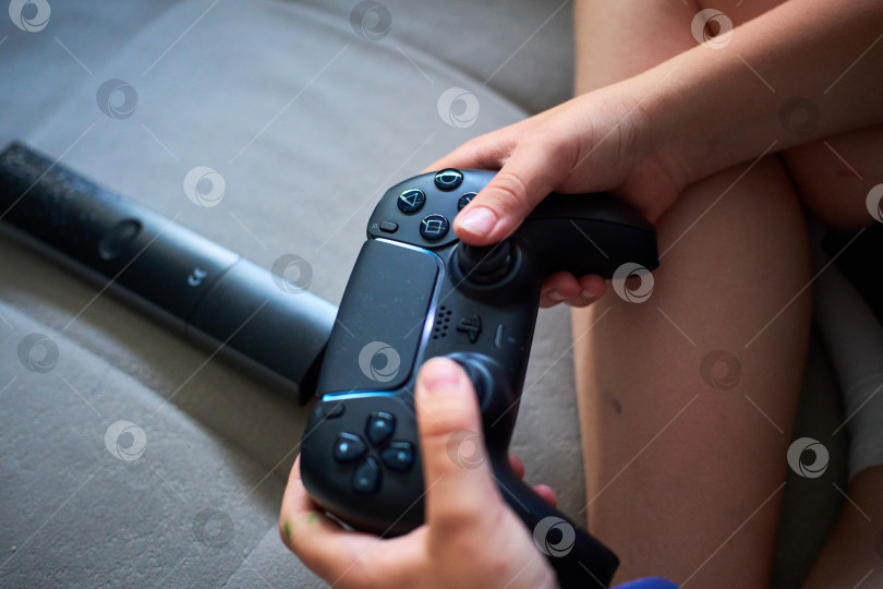 Скачать Тюмень, Россия - 8 июля 2025 года: Sony PlayStation 5 Молодой геймер удобно устроился в кресле, сосредоточенный на игре в свою любимую игру фотосток Ozero