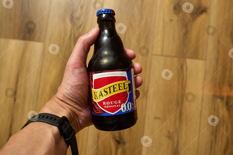 Скачать Тюмень, Россия - 3 декабря 2025 года: бутылка пива Kasteel Rouge установлена вертикально на полированном деревянном полу фотосток Ozero