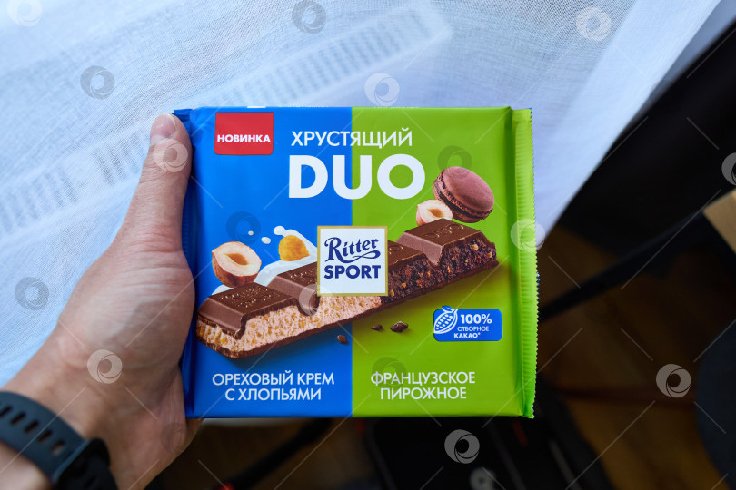 Скачать Тюмень, Россия - 3 декабря 2025 года: участник спортивного дуэта Ritter держит в руках плитку шоколада с ореховым кремом фотосток Ozero