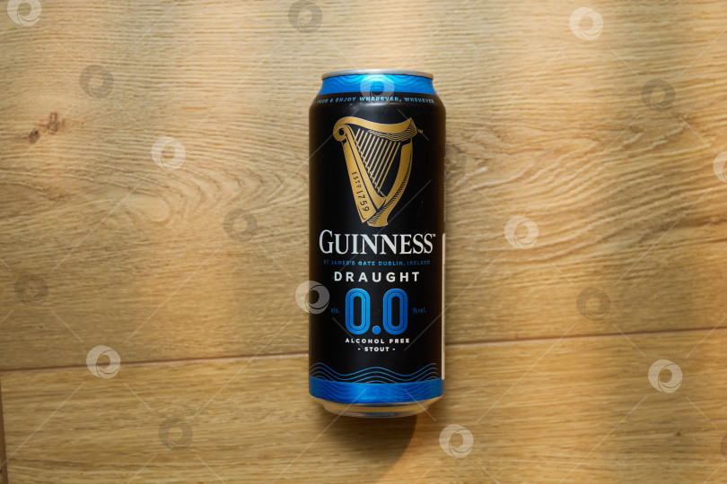 Скачать Тюмень, Россия - 11 декабря 2025 года: Банка безалкогольного пива guinness стоит на мягкой поверхности, демонстрируя выбор для тех, кто предпочитает фотосток Ozero