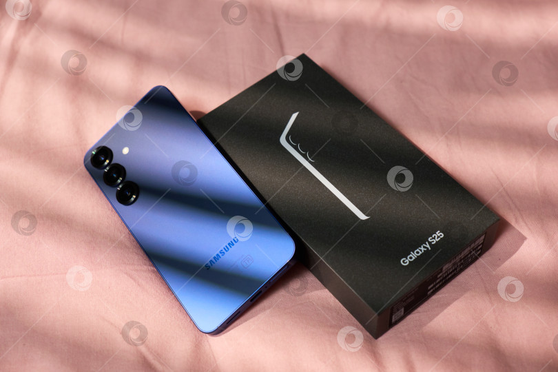 Скачать Тюмень, Россия- 11 декабря 2025 года: Модели Samsung S25 демонстрируются на простом фоне с мягким светом и тенями в дневное время фотосток Ozero
