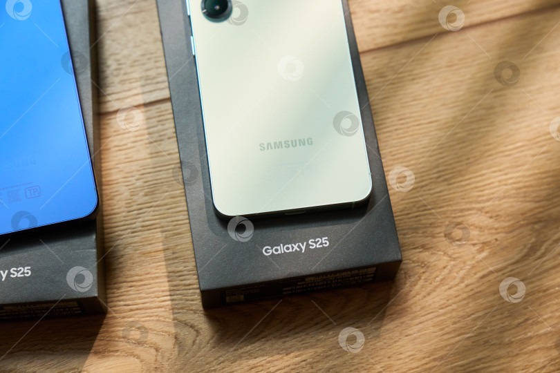 Скачать Тюмень, Россия- 11 декабря 2025 года: Модели Samsung S25 демонстрируются на простом фоне с мягким светом и тенями в дневное время фотосток Ozero
