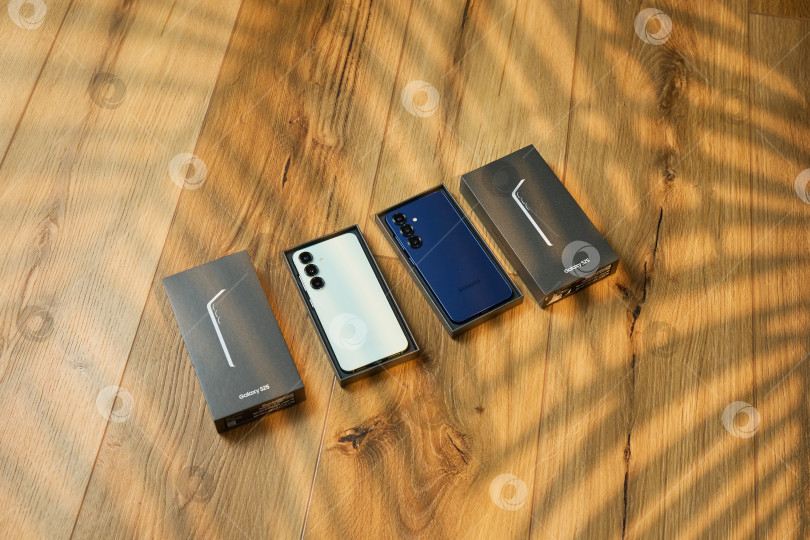 Скачать Тюмень, Россия - 11 декабря 2025 года: Демонстрация Samsung S25 в различных цветах, размещенная на деревянной поверхности. фотосток Ozero