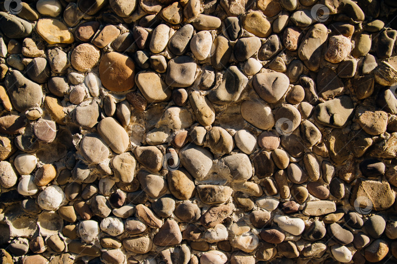 Скачать Стена серая.Абстрактный фон.Текстура каменной стены. Каменная стена, сложенная из круглых булыжников. На стену падает солнечный свет. фотосток Ozero