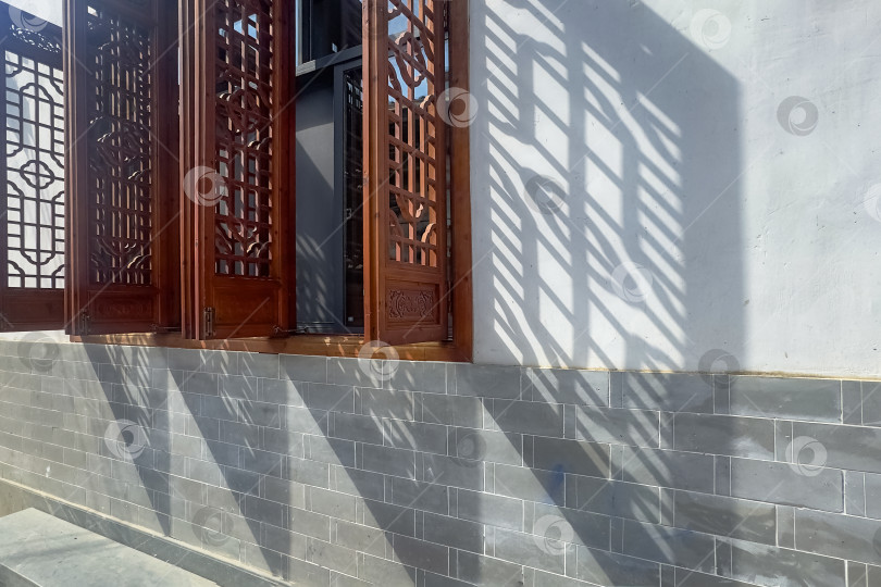 Скачать Традиционное деревянное окно отбрасывает резкие тени на серую кирпичную стену фотосток Ozero