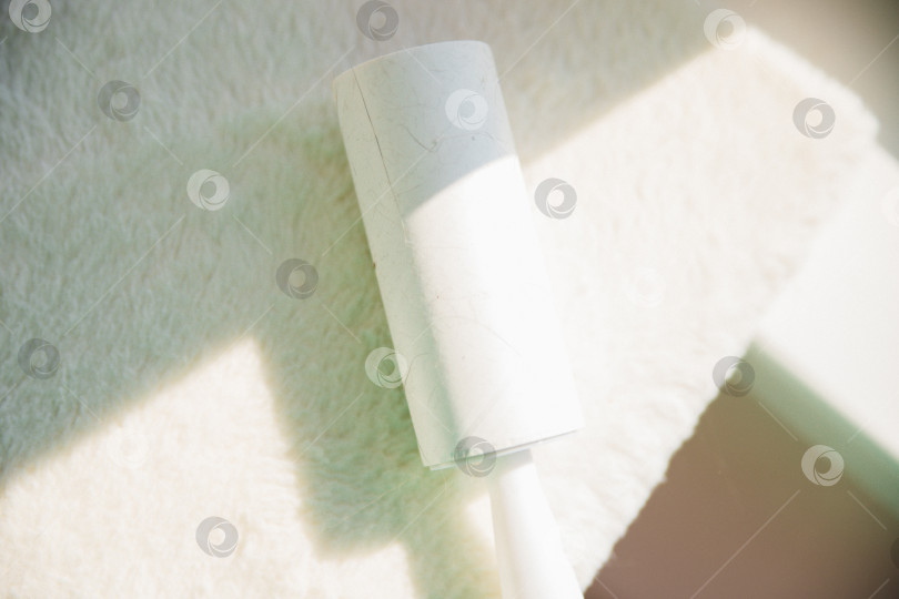 Скачать Белая поверхность мягкой мебели с липкой подушкой. Чистка мягкой мебели от пыли, шерсти и волосяного покрова. фотосток Ozero