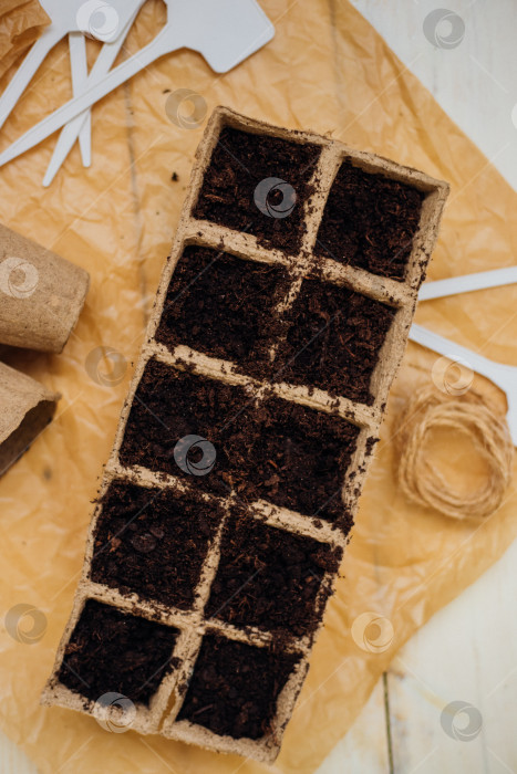 Скачать Вид сверху на семена и ячейки с почвой на деревянном фоне. Выращивание рассады в торфяных стаканчиках. Концепция весеннего озеленения дома. фотосток Ozero