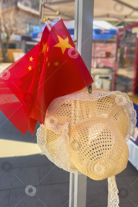 Скачать Рядом с плетеной шляпой висит маленький красный флажок с желтыми звездами. Китай. фотосток Ozero