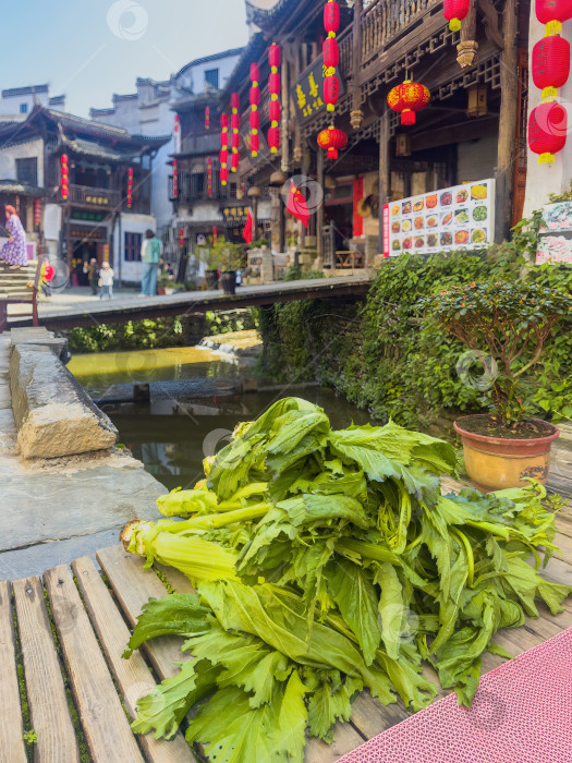 Скачать Свежая зелень горчицы лежит на деревянных досках рядом с каналом фотосток Ozero