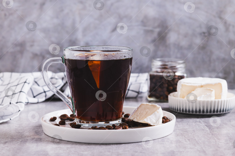 Скачать Черный кофе с кусочком сыра бри в бокале на столе фотосток Ozero