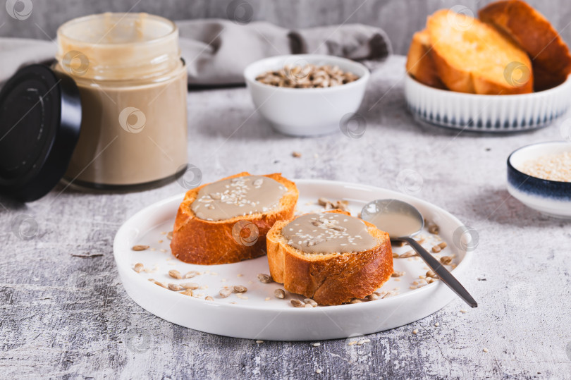 Скачать Урбеч из семян кунжута и подсолнечника на хлебе на тарелке фотосток Ozero