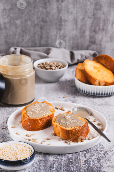 Скачать Урбеч из семян кунжута и подсолнечника на хлебе на тарелке, вид сверху фотосток Ozero