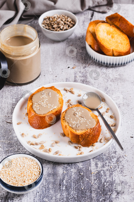 Скачать Тосты с кунжутом и подсолнечной тахини на тарелке на столе, вид сверху фотосток Ozero