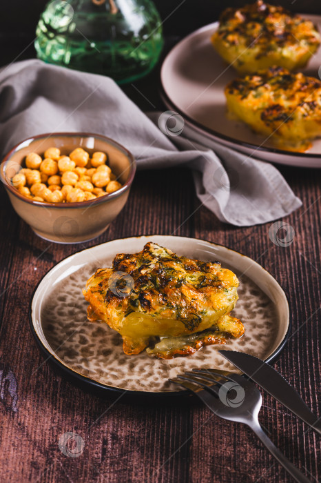Скачать Хрустящий печеный картофель с сыром, чесноком и укропом на тарелке в вертикальном положении фотосток Ozero