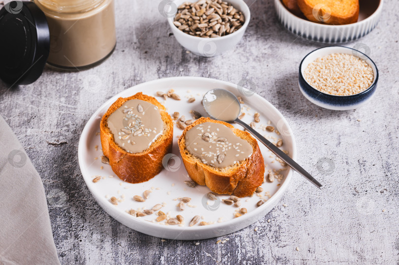 Скачать Тосты с кунжутом и подсолнечной тахини на тарелке на столе фотосток Ozero