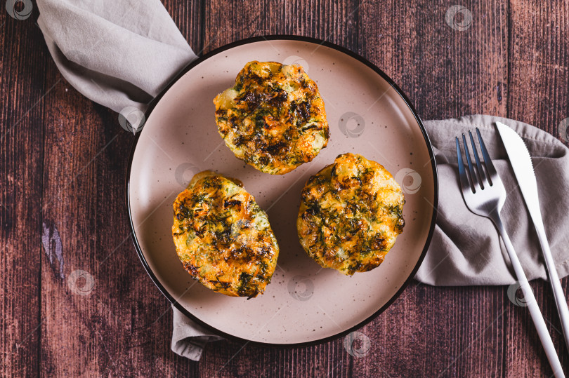 Скачать Половинки картофеля, запеченные с сыром, чесноком и зеленью, крупным планом на тарелке на столе, вид сверху фотосток Ozero