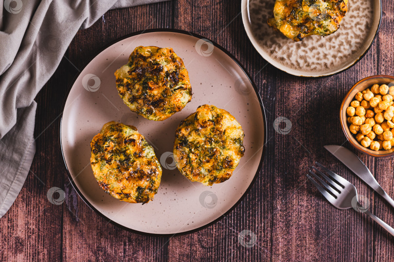 Скачать Половинки картофеля, запеченные с сыром, чесноком и зеленью на тарелке на столе, вид сверху фотосток Ozero