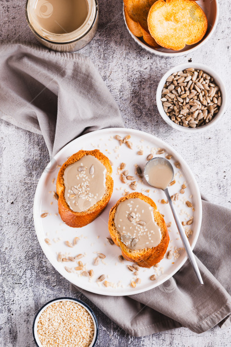 Скачать Тосты с кунжутом и подсолнечной тахини на тарелке, установленной на столешнице, в вертикальном положении фотосток Ozero