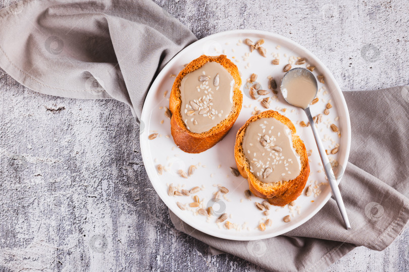 Скачать Урбеч из семян кунжута и подсолнечника крупным планом на хлебе на тарелке вид сверху фотосток Ozero