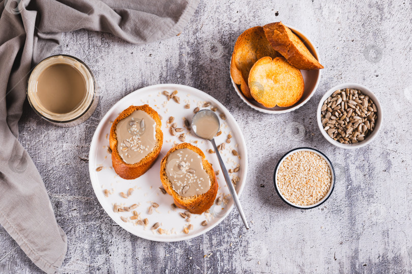 Скачать Урбеч из семян кунжута и подсолнечника на хлебе на тарелке вид сверху фотосток Ozero